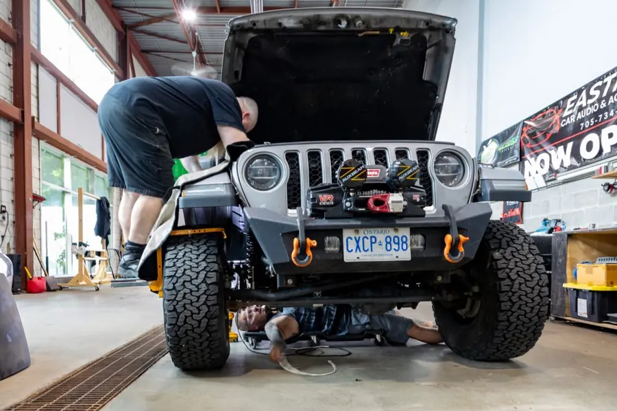 Technician working on a Jeep Wrangler with a winch bumper inside the Eastman shop